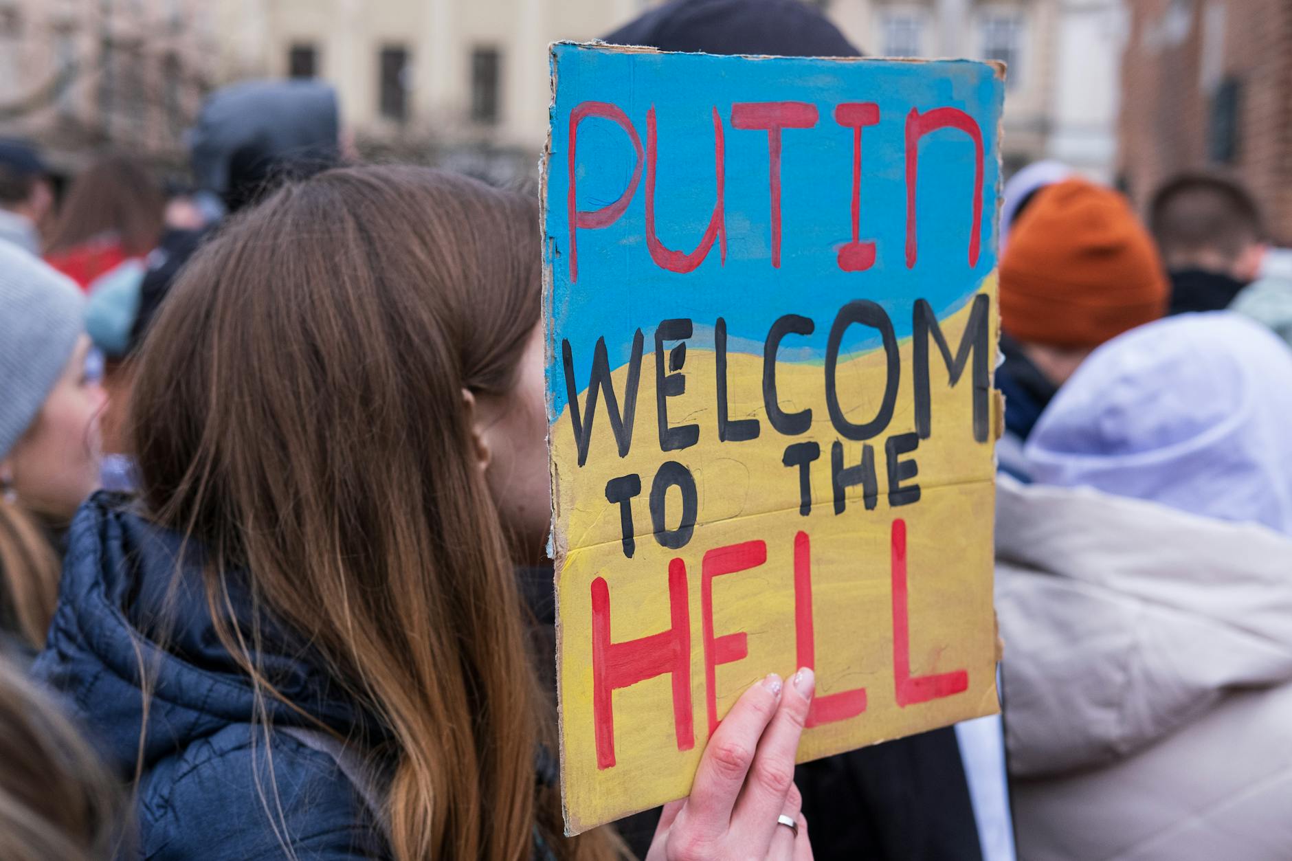 Protester holding a colorful placard at an outdoor rally with strong messaging.