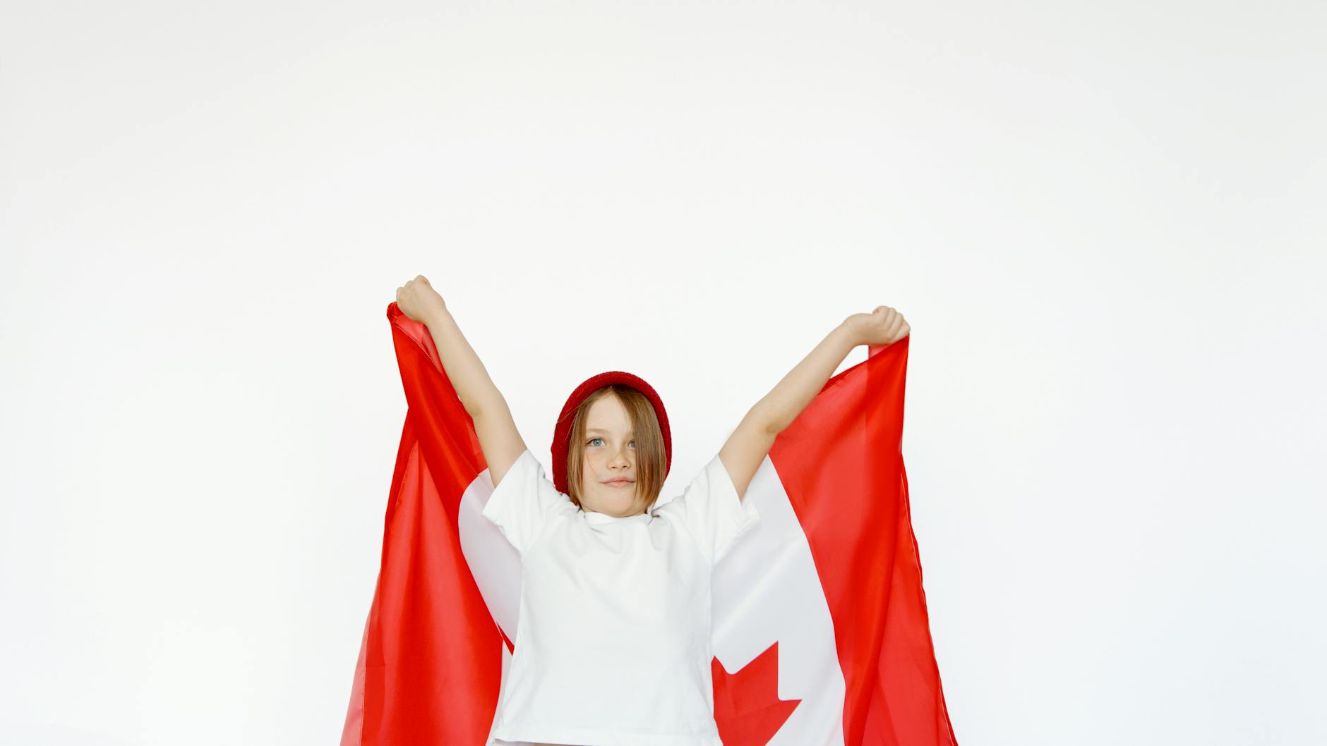 A child joyfully holding a Canadian flag, celebrating patriotism and freedom.