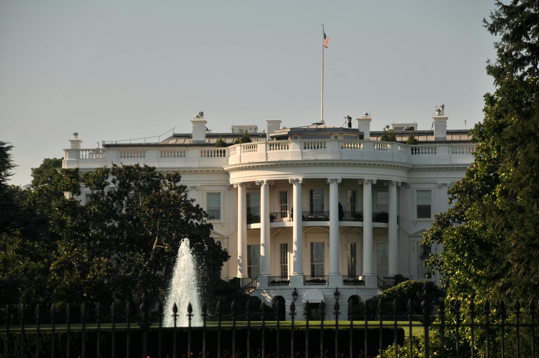 The stately White House with its iconic architecture surrounded by lush greenery, featuring a majestic fountain.