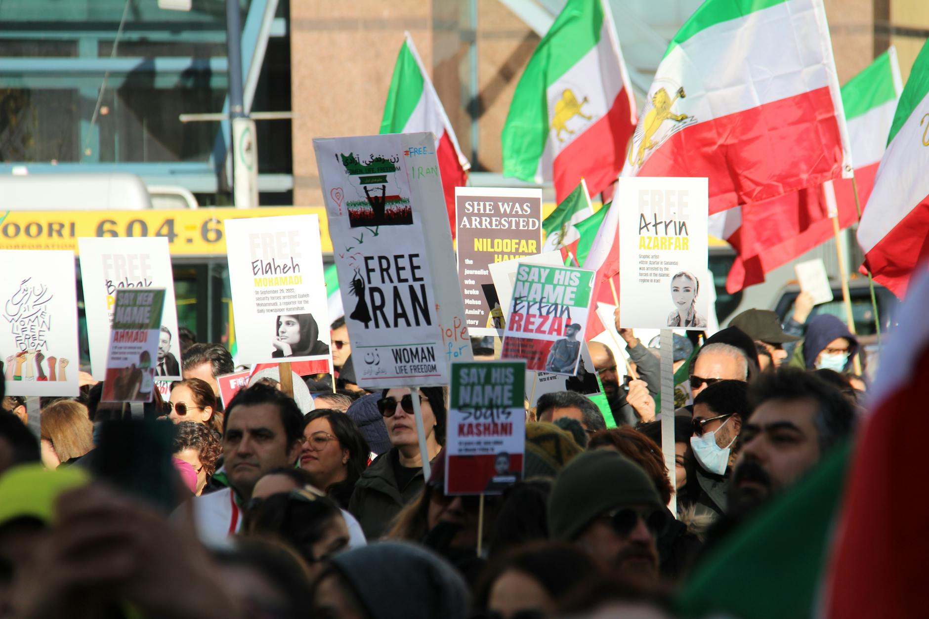 Protesters in Vancouver rally for justice and freedom for Iranian women, holding signs and flags.