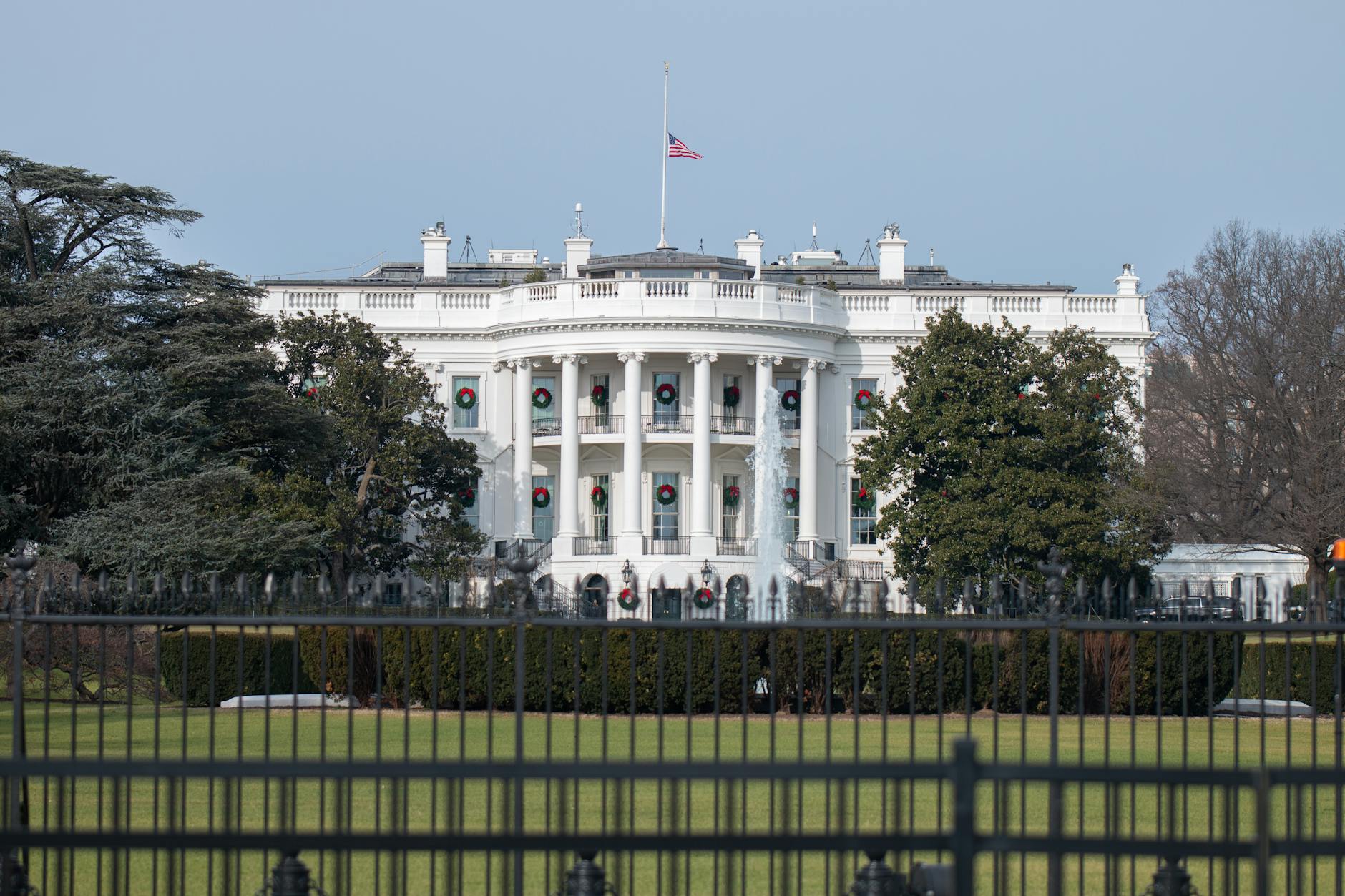 Front view of the iconic White House in Washington, DC, adorned with wreaths and the American flag.