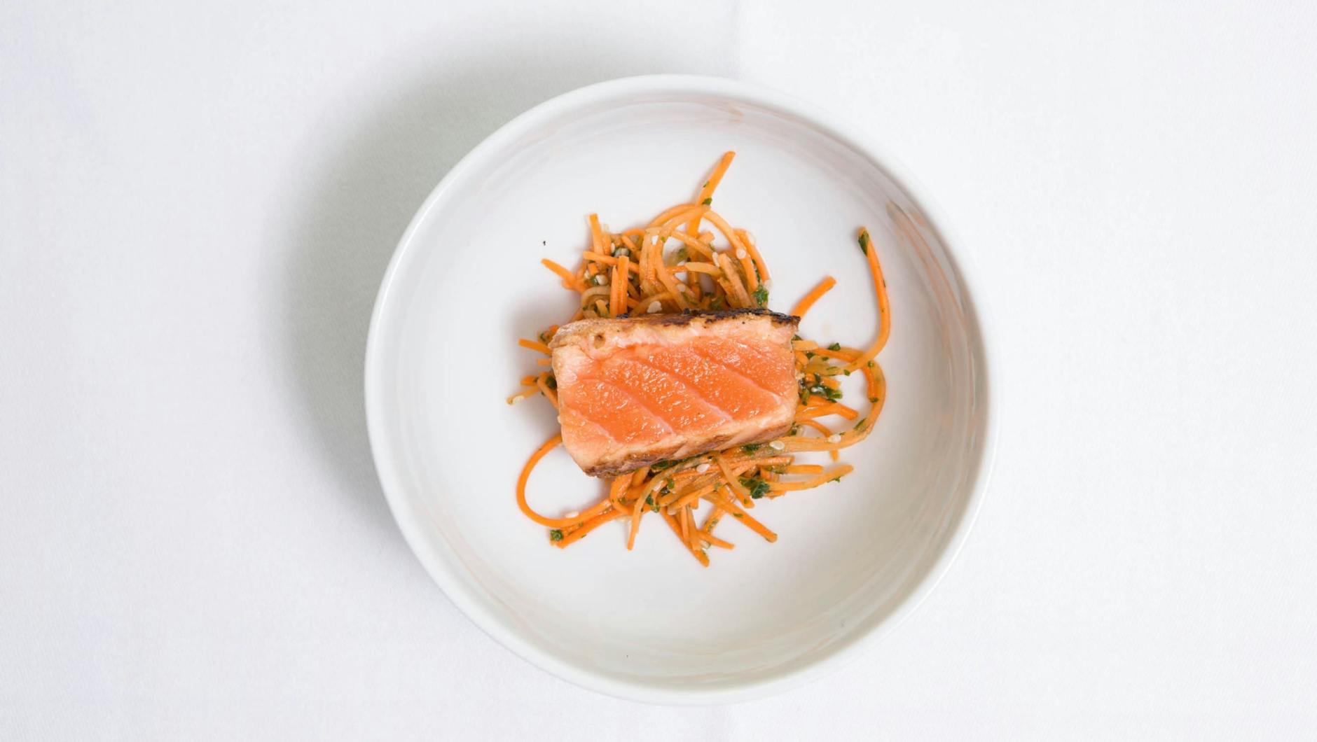 Top view of salmon filet served on a bed of spiralized vegetables in a minimalist setting.