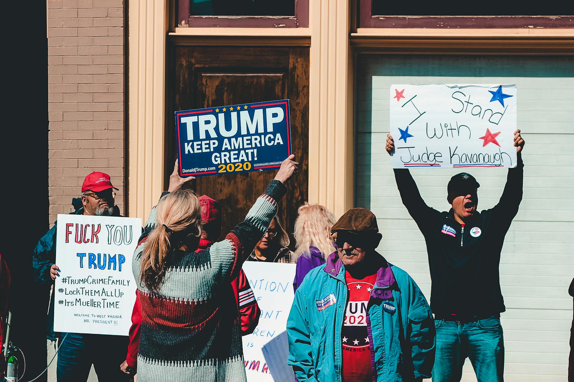 A group of people at a political rally in Wheeling, West Virginia, supporting different 2020 election campaigns.