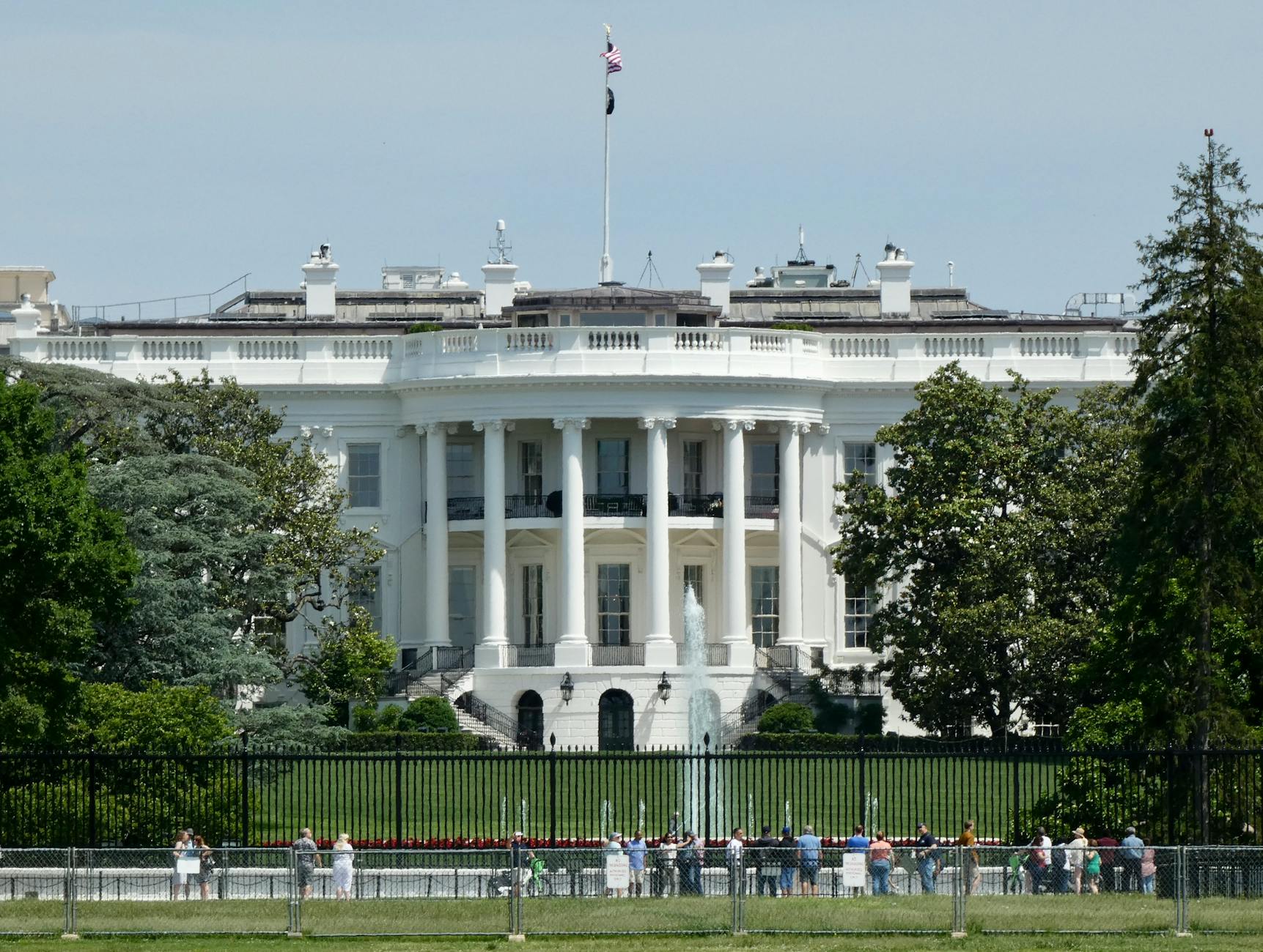 The White House in Washington DC, with tourists viewing from the lawn.