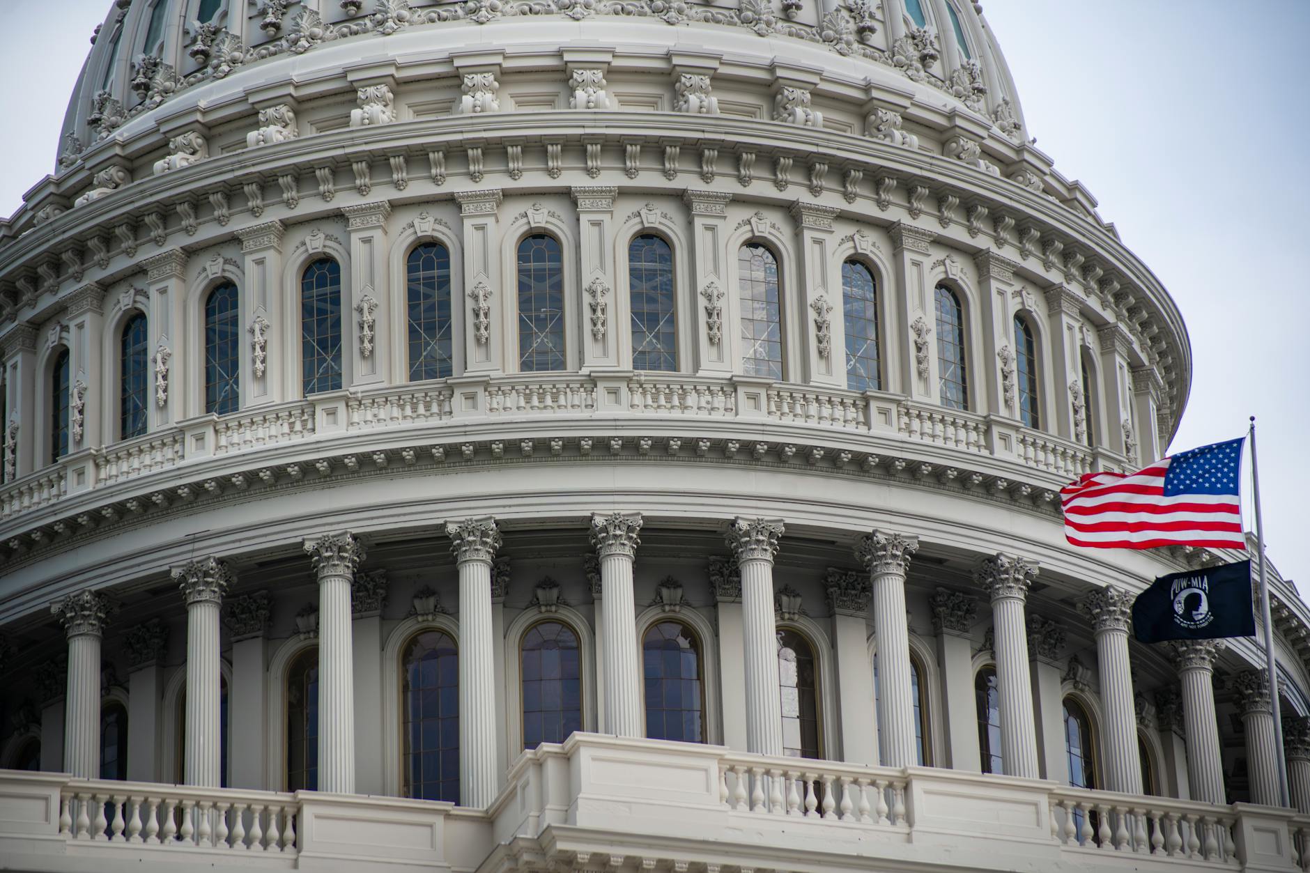 Detailed view of the US Capitol dome with the American flag flying nearby in Washington D.C.