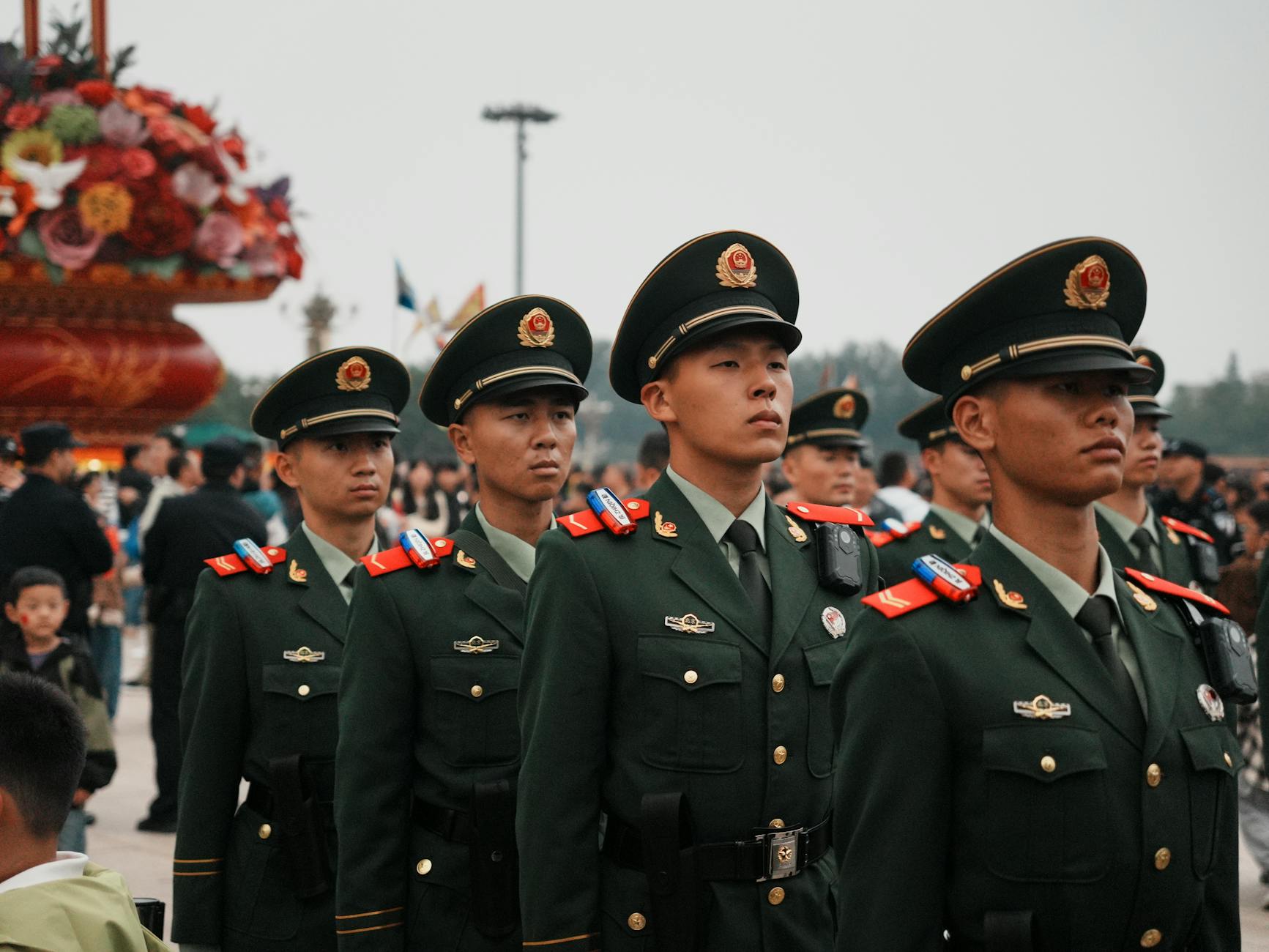 A group of soldiers in green uniforms marching outdoors, part of a ceremonial parade.