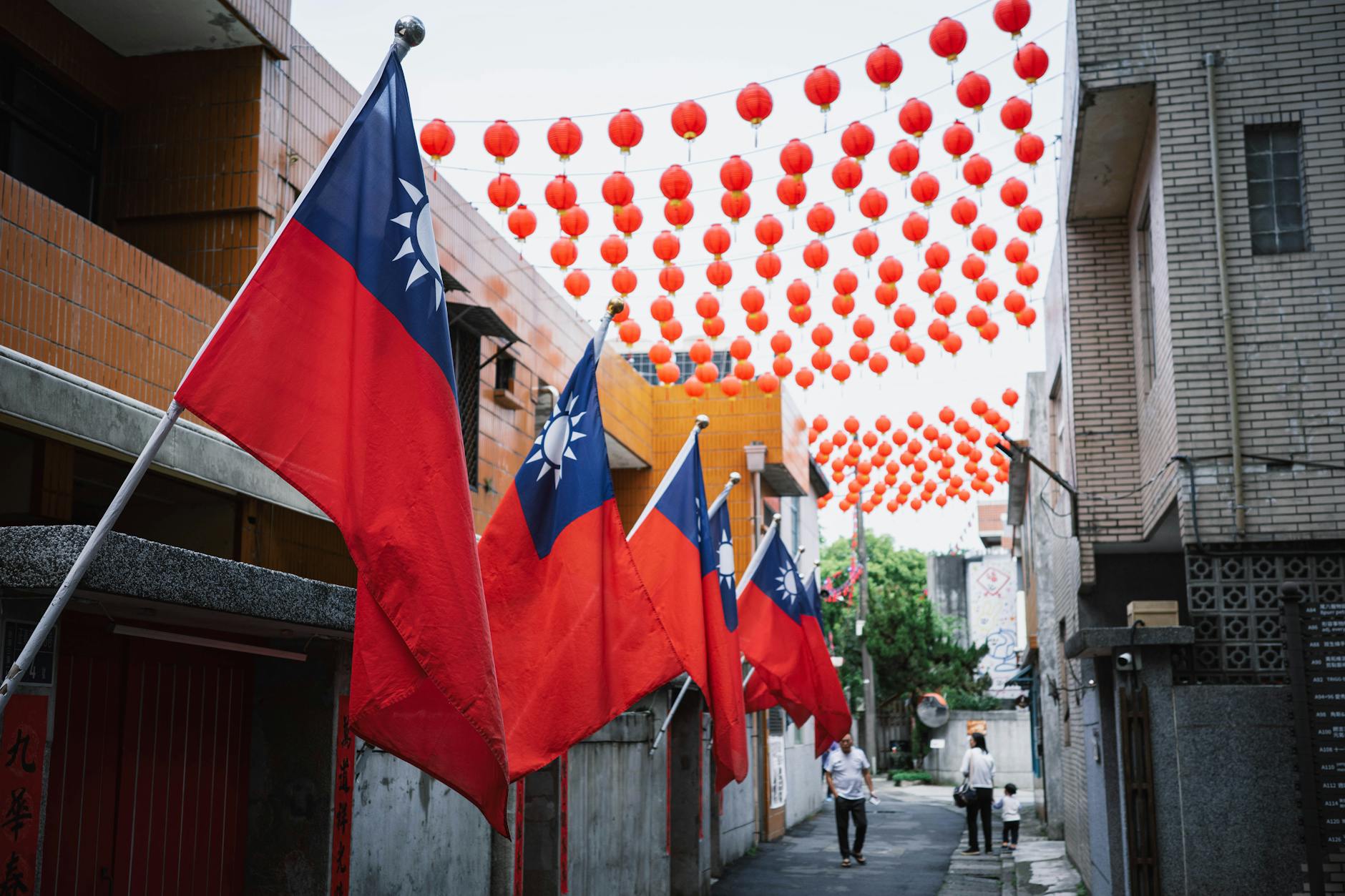 Colorful Taiwanese flags and red lanterns adorn an alley in New Taipei City, Taiwan, creating a festive atmosphere.