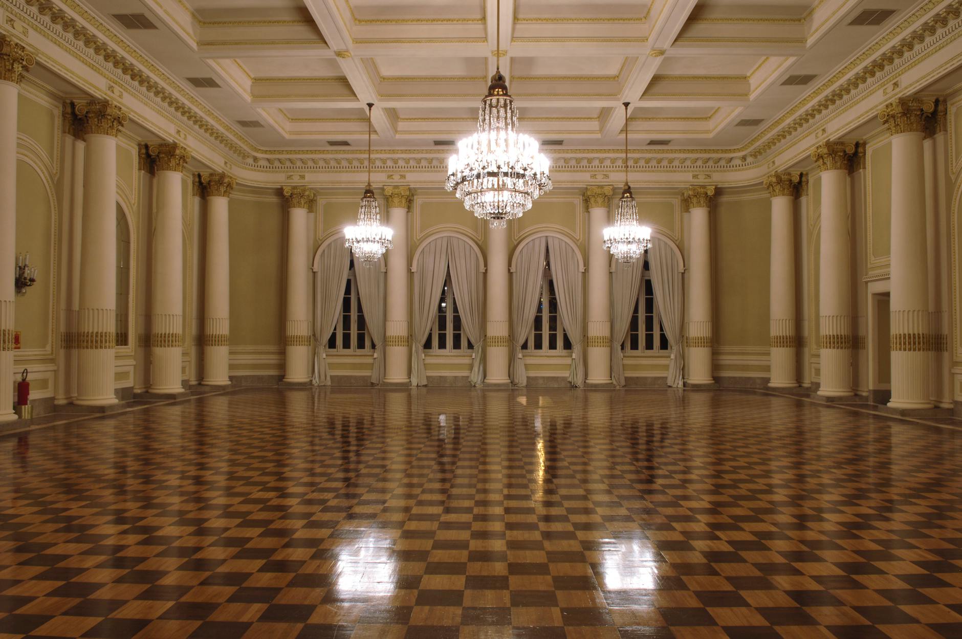 Luxurious ballroom with gleaming chandeliers and polished checkered floor, perfect for formal events.