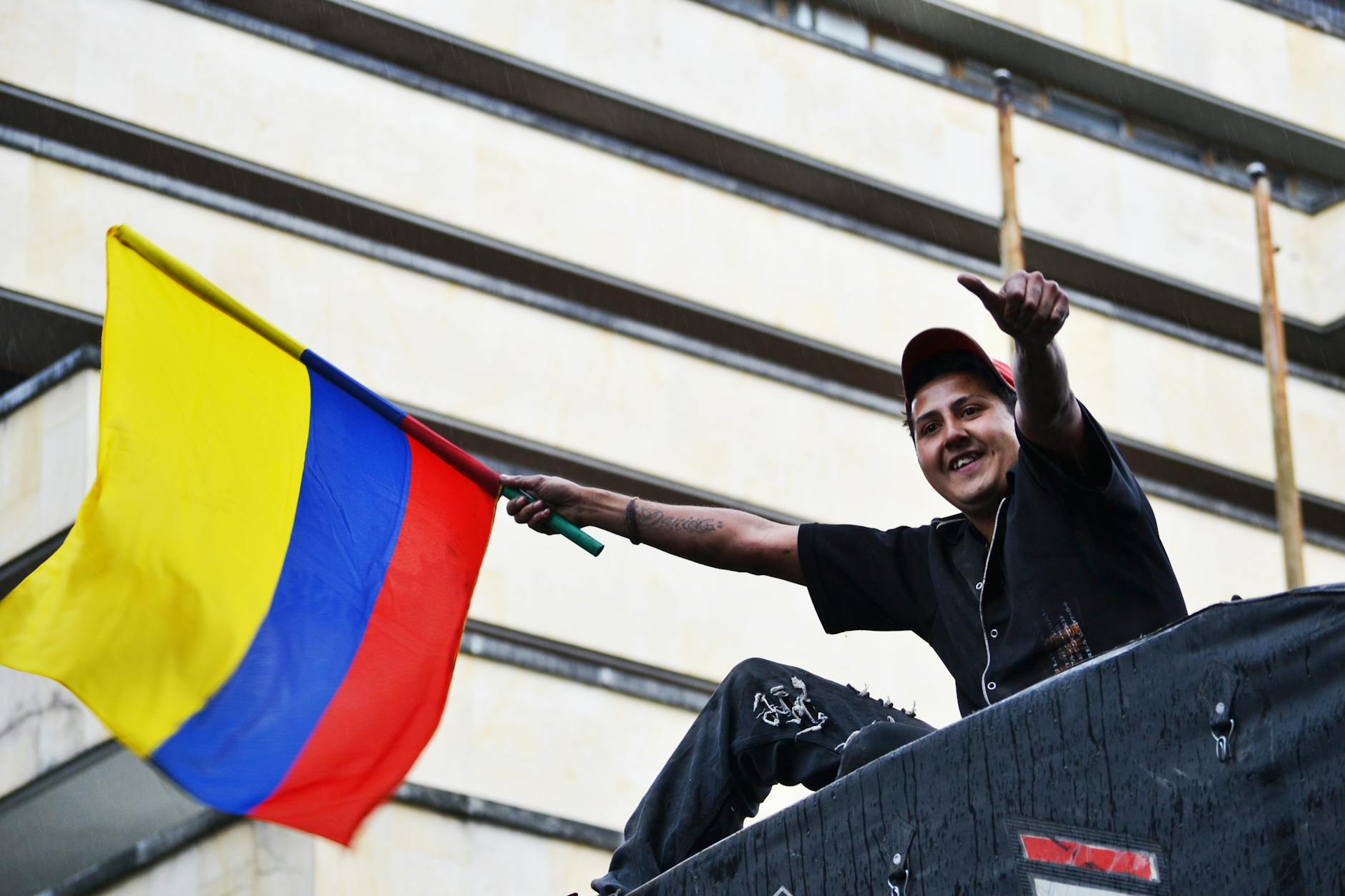 White House Prepares satire image: A man joyfully waves the Colombian flag in Bogotá, showing national pride.