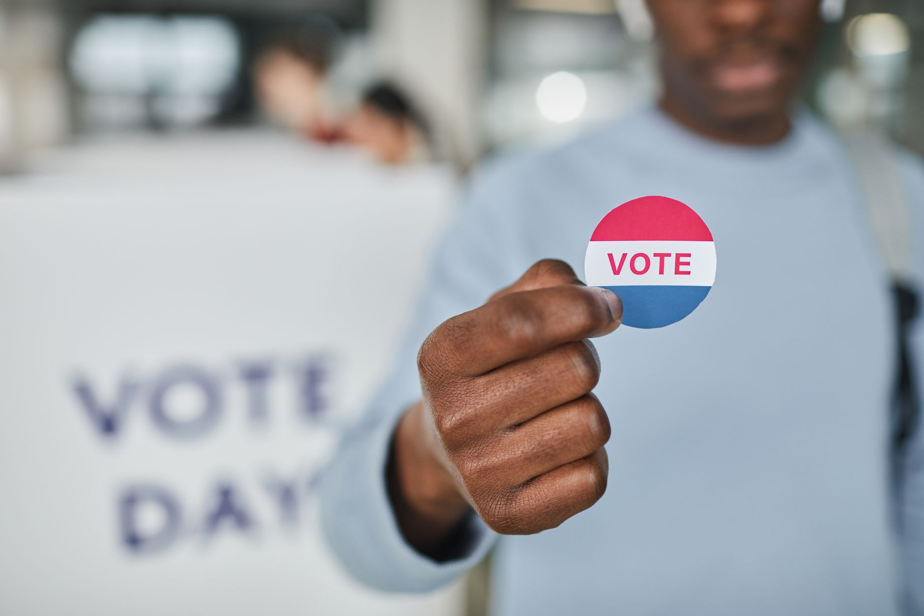Congress Maine satire image: Close-up image of a person holding a vote sticker, symbolizing participation and civic duty.