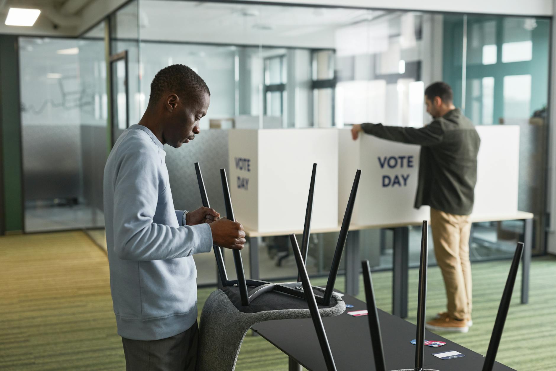 Election Wisconsin satire image: Men preparing voting booths indoors for election day, enhancing democracy.