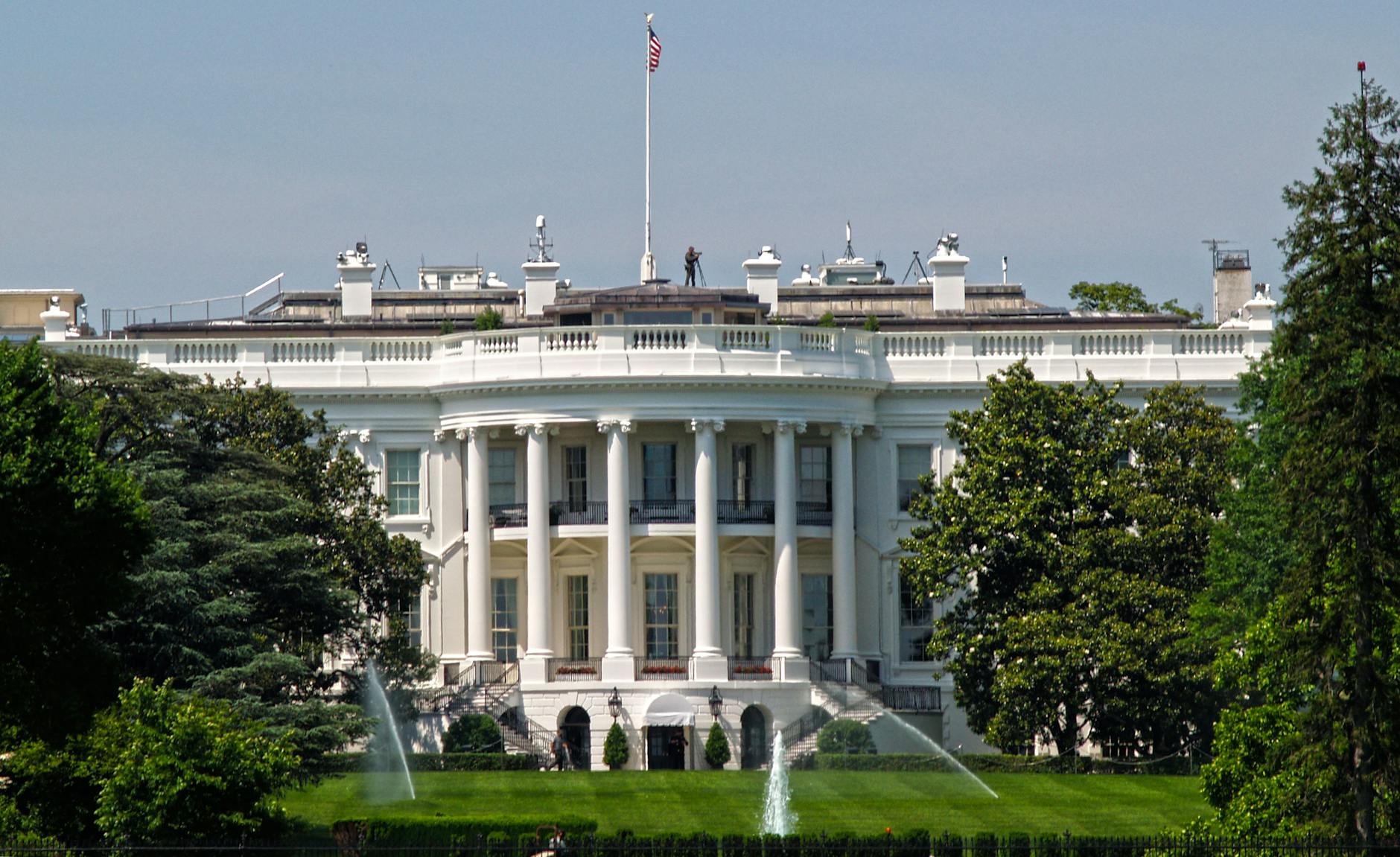 Iconic view of the White House with surrounding gardens and American flag in Washington, DC.