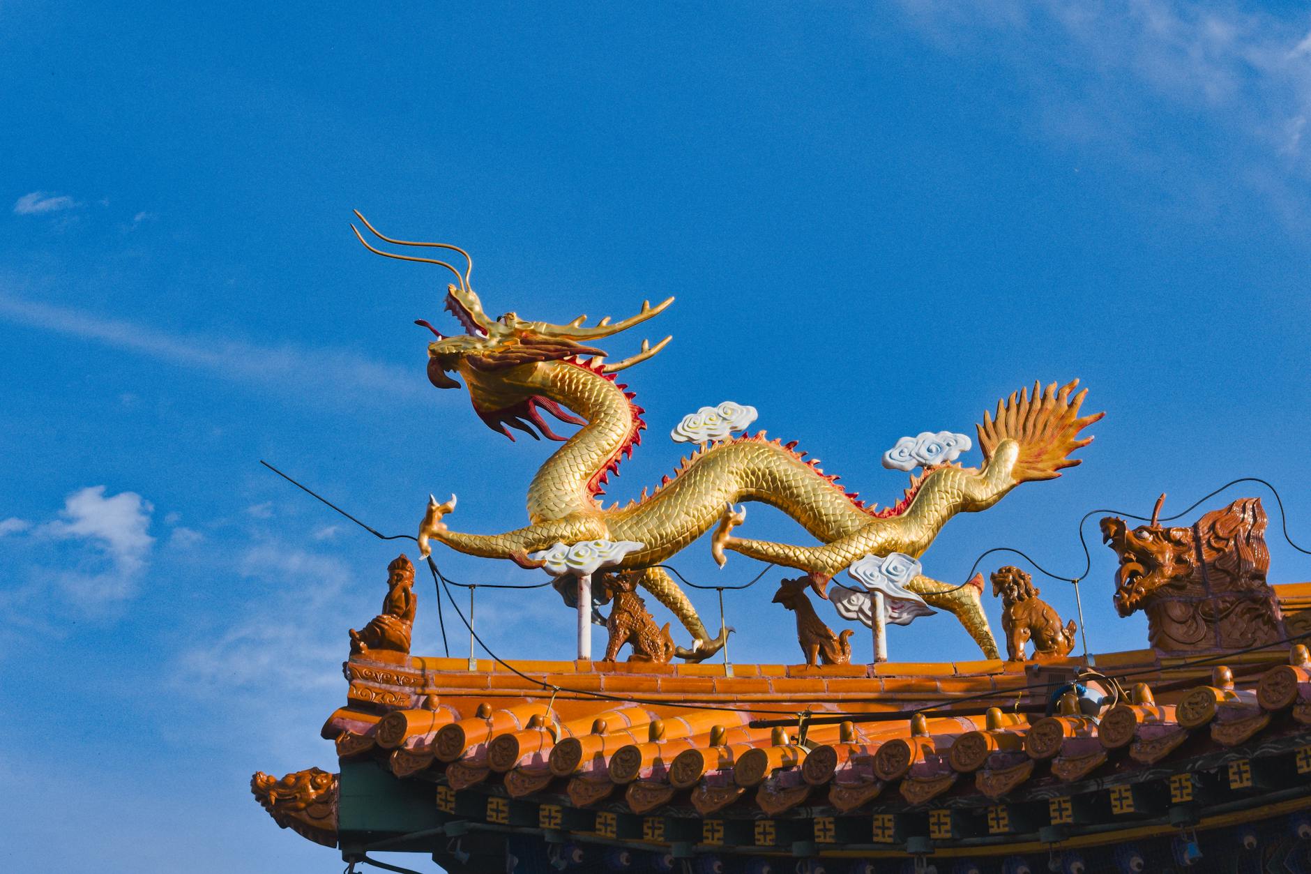 Close-up of a golden dragon sculpture on a temple roof in Hohhot, Inner Mongolia, against a blue sky.