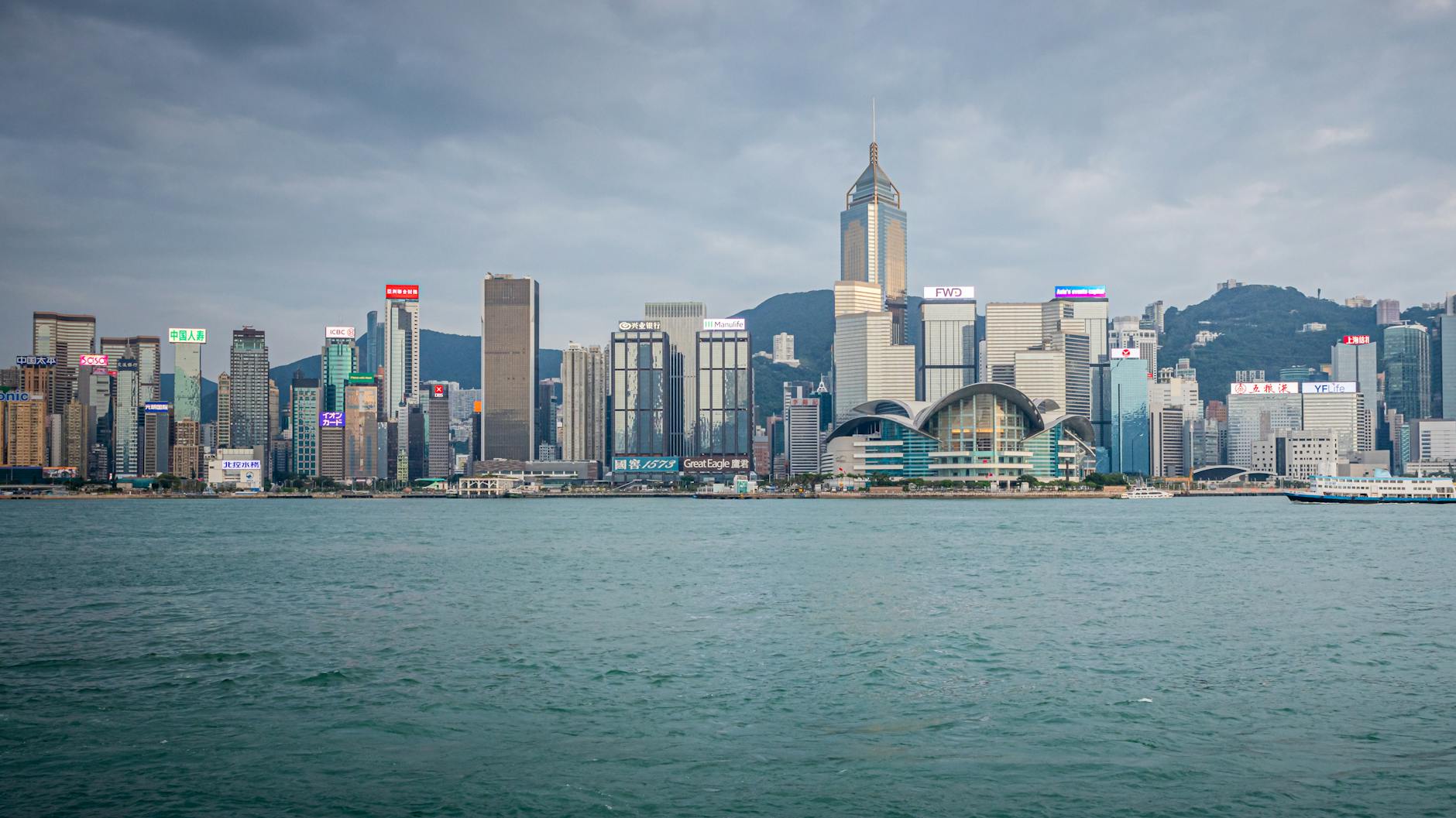 Spectacular daytime view of Hong Kong skyline with harbor in foreground.