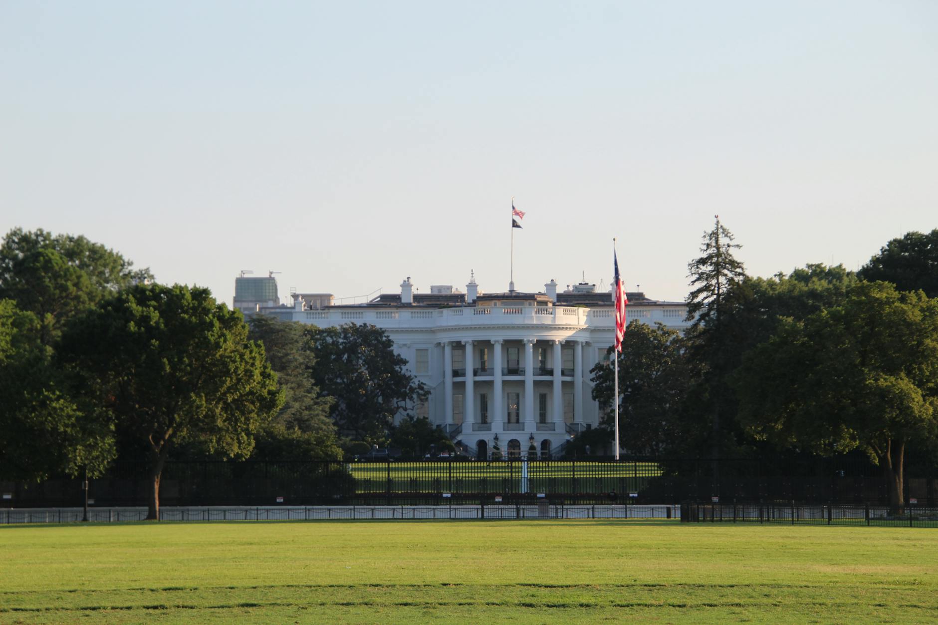 The White House surrounded by greenery under a clear sky.