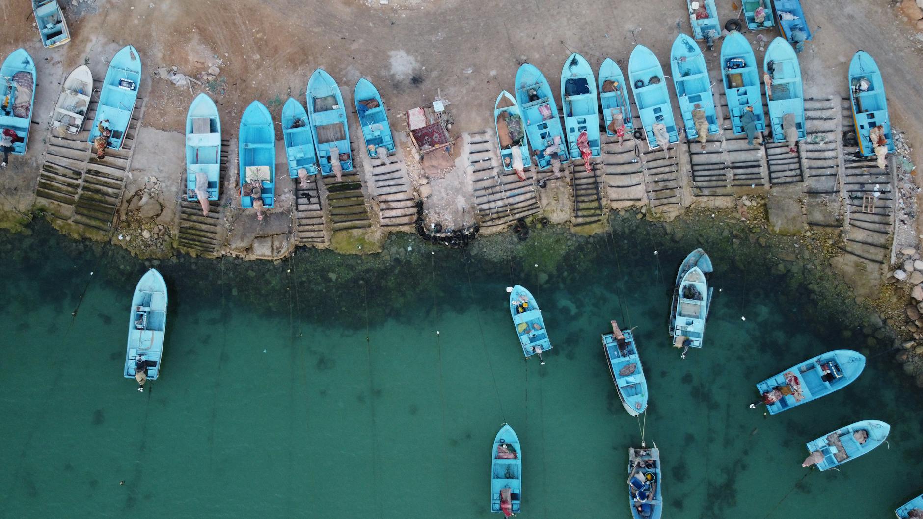 Aerial view of blue boats docked at a shoreline in Asaluyeh, Iran.