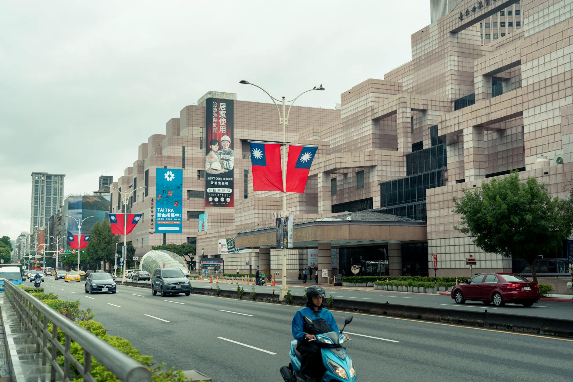 Taipei street scene featuring busy traffic, prominent mall, and national flags.