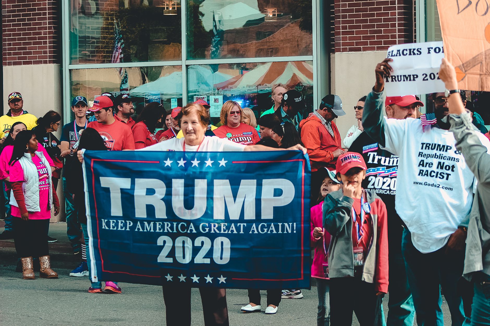 Trump Offers satire image: A crowded political rally in Wheeling, showcasing Trump supporters with banners and signs.
