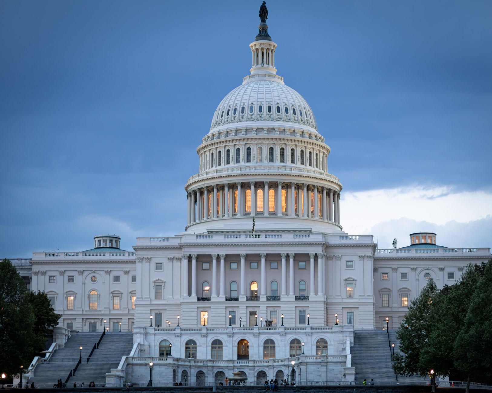 satire-image-20 Congress Iowa satire image: The iconic United States Capitol Building illuminated against a twilight sky.