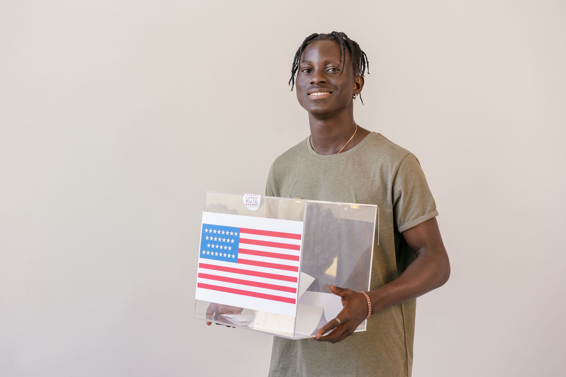 satire-image-21 Congress Kentucky satire image: Smiling young adult holding a ballot box with an American flag, emphasizing the importance of voting.