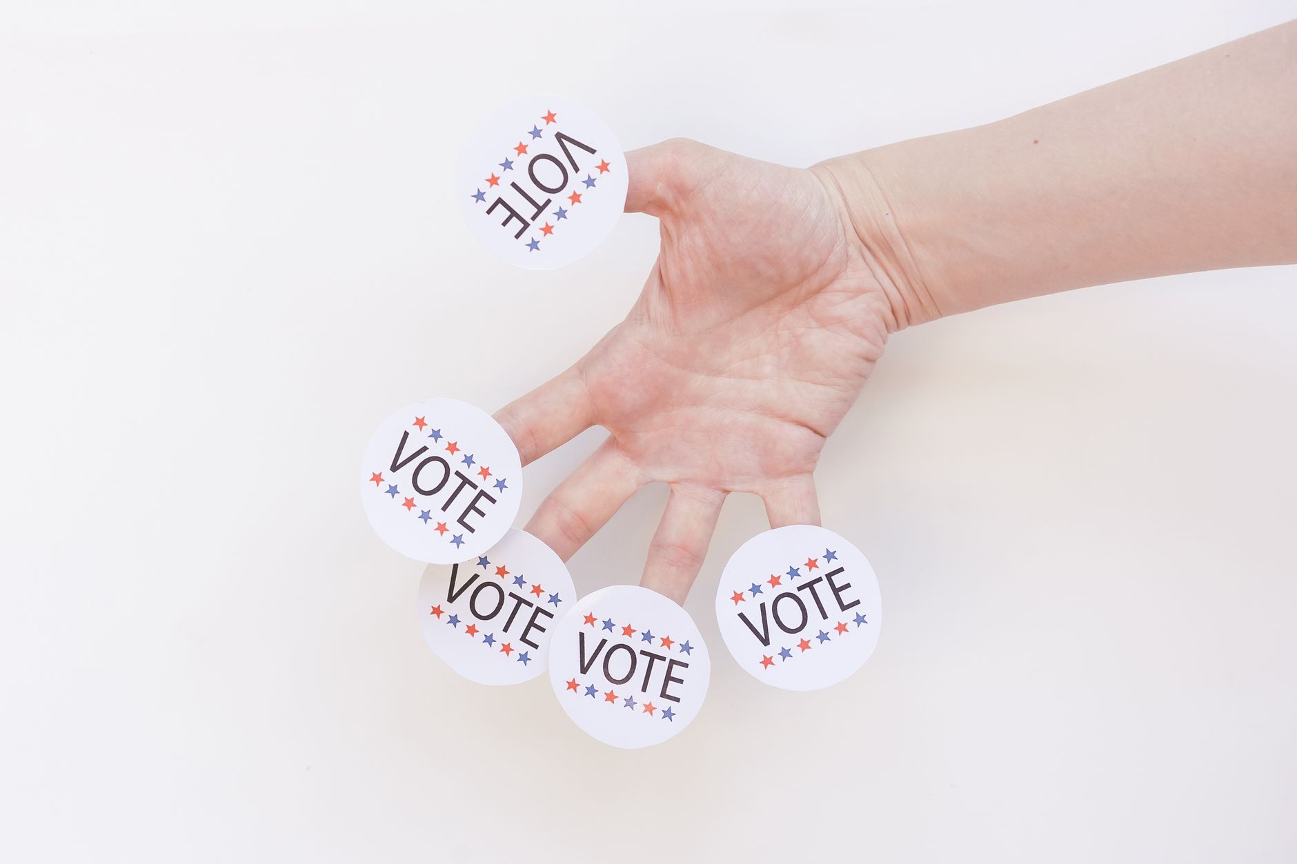 satire-image-32 Election California satire image: A hand displays several 'Vote' stickers on a white background, symbolizing political participation.