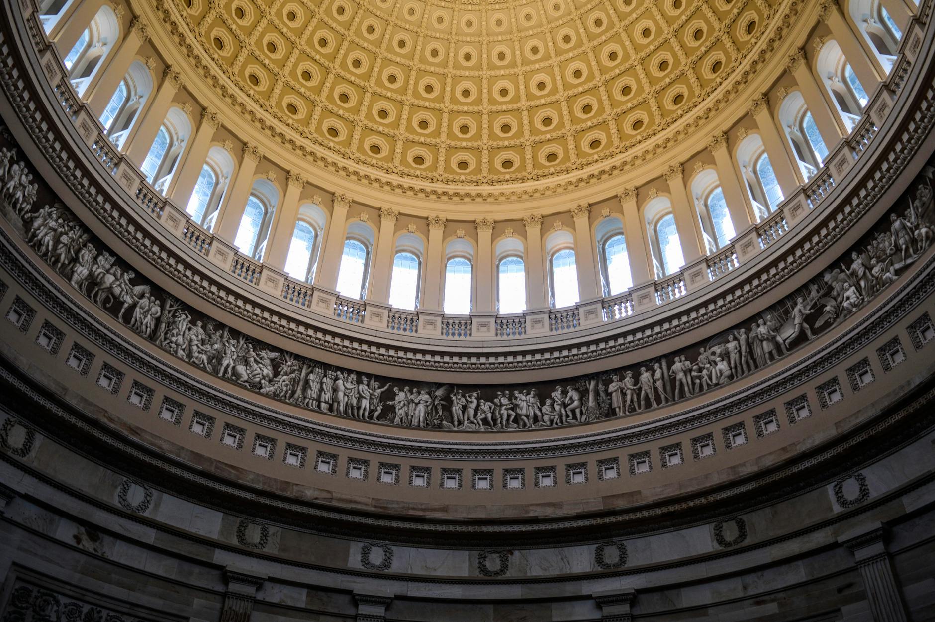 satire-image-38 Congress Maine satire image: From below of carved stone bas relief frieze and arched windows decorating dome of United States Capitol