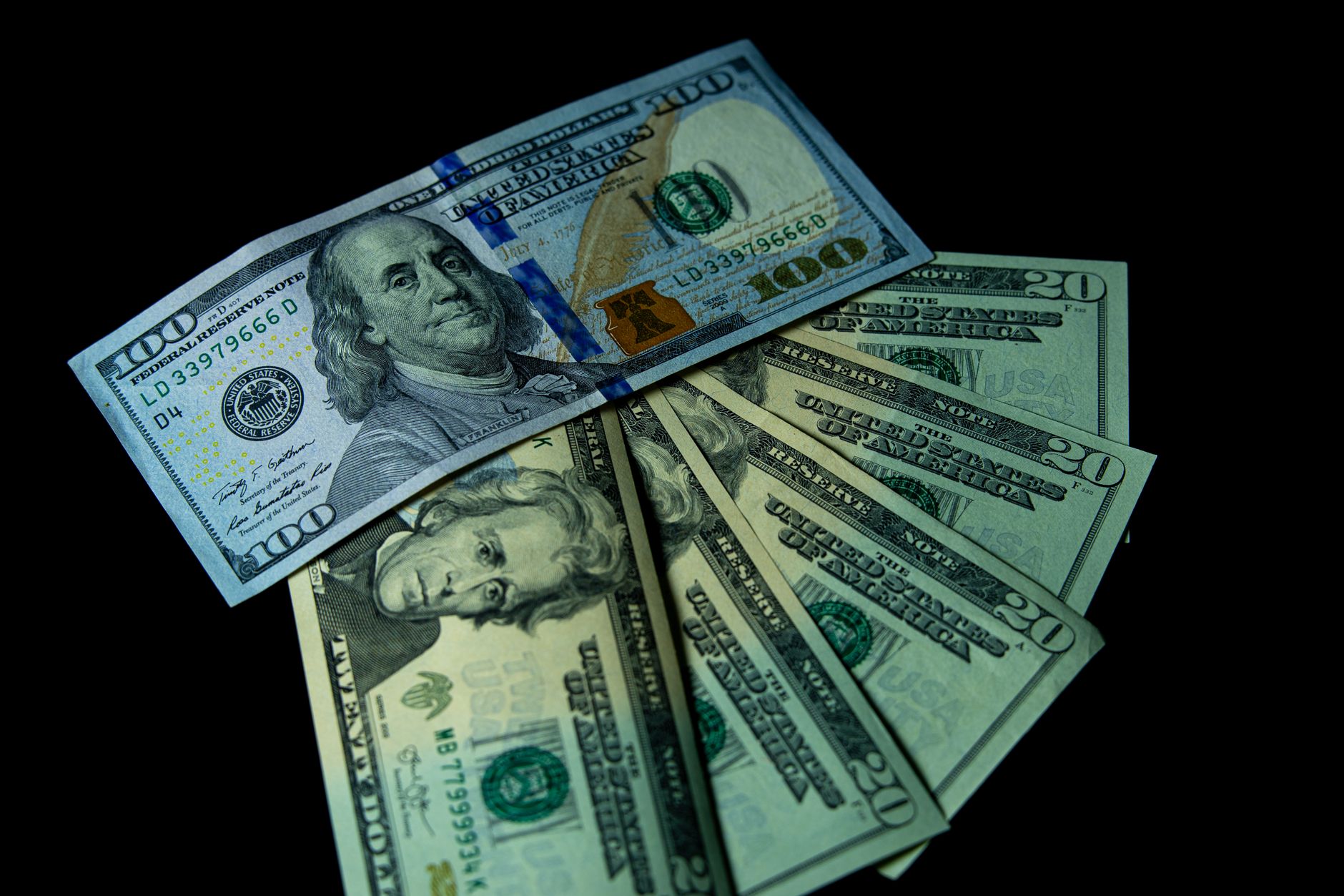 satire-image-41 Inflation Treasury satire image: Close-up image of varied US dollar bills on a black background.