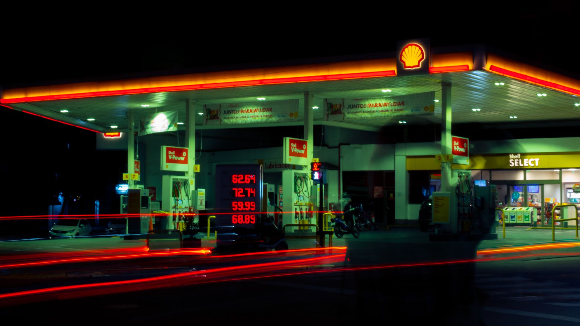 White House Files satire image: Illuminated Shell gas station with long exposure light trails at night.