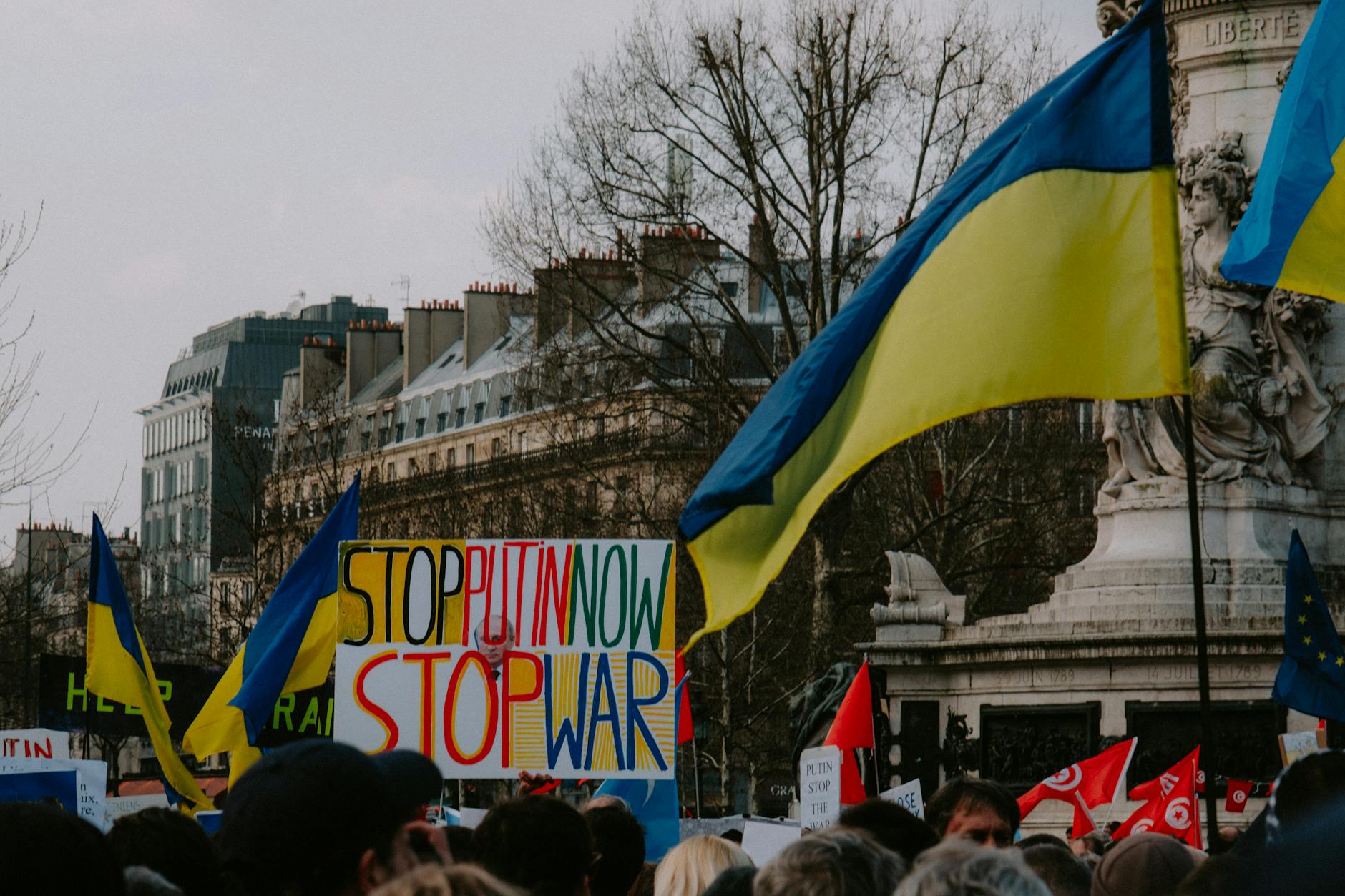Trump Creates satire image: A dynamic crowd in Paris rallies with Ukrainian flags and anti-war signs, advocating peace.