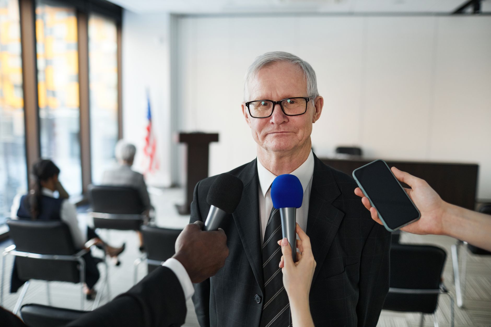 satire-image-53 Trump Rule satire image: Senior man in formal attire being interviewed in a conference room.