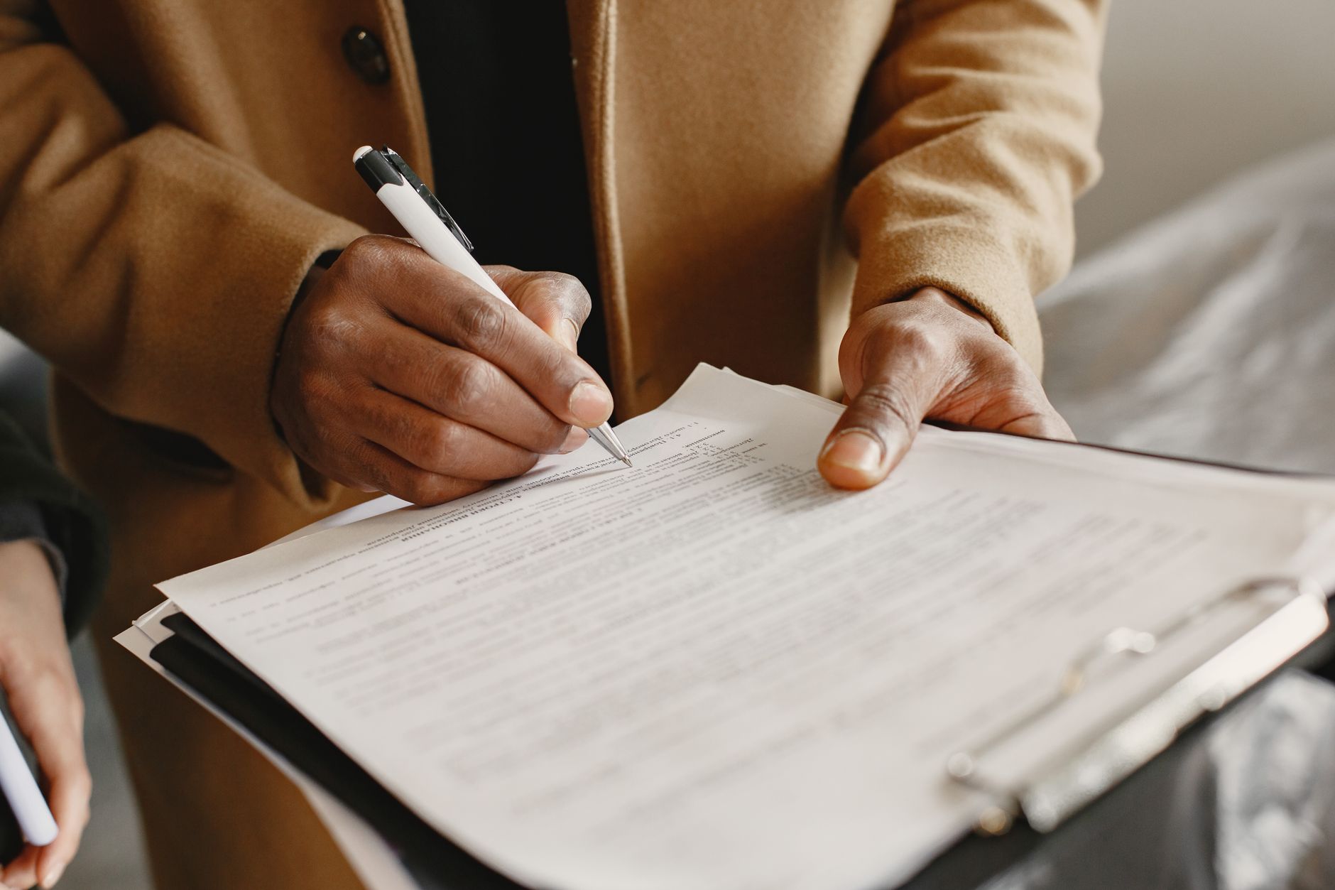 satire-image-66 Election Netanyahu satire image: Close-up of a person signing a contract on a clipboard, focusing on legal formalities.