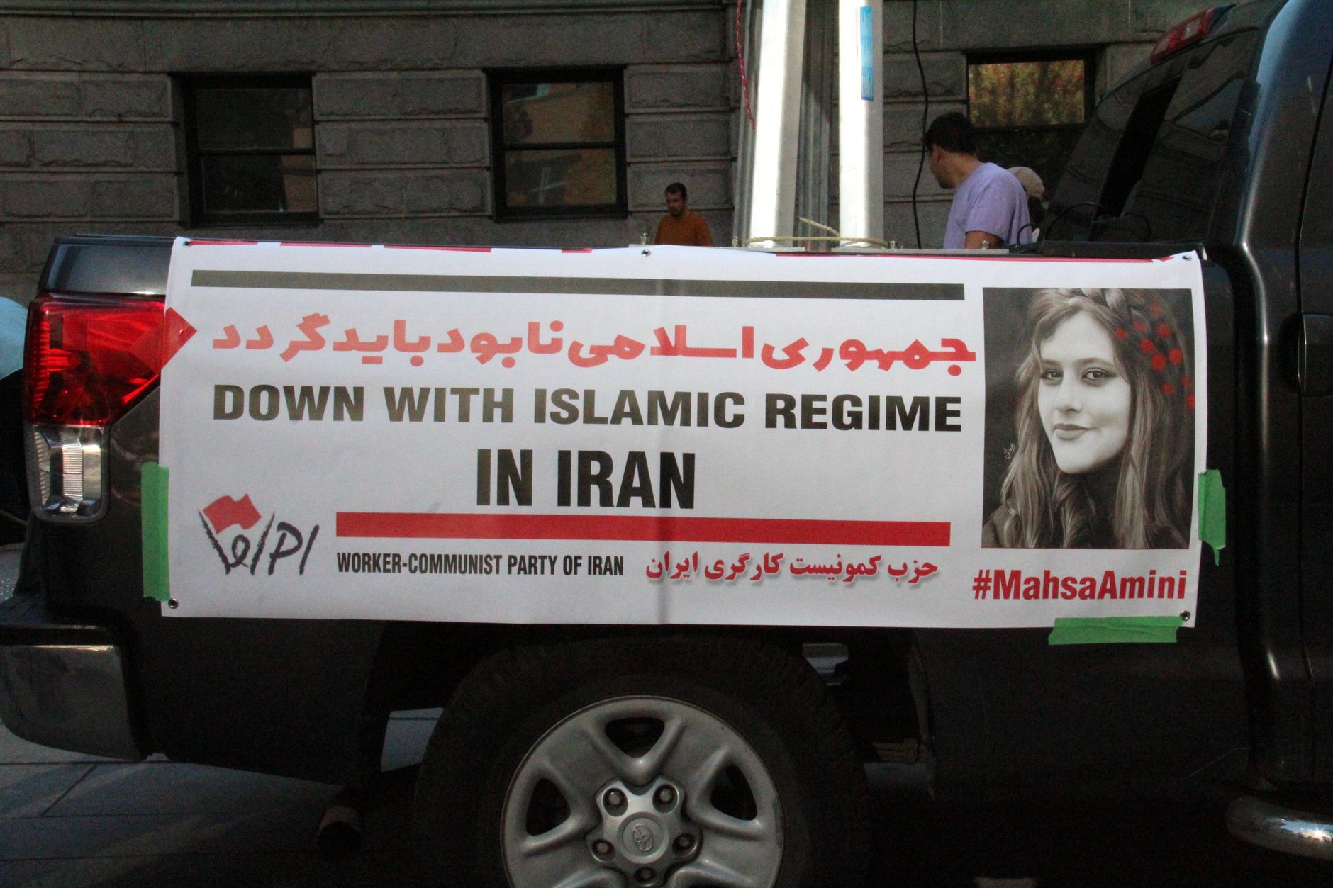Trump Reclassifies satire image: Demonstration in Vancouver with a banner against Iran's regime, highlighting Mahsa Amini.
