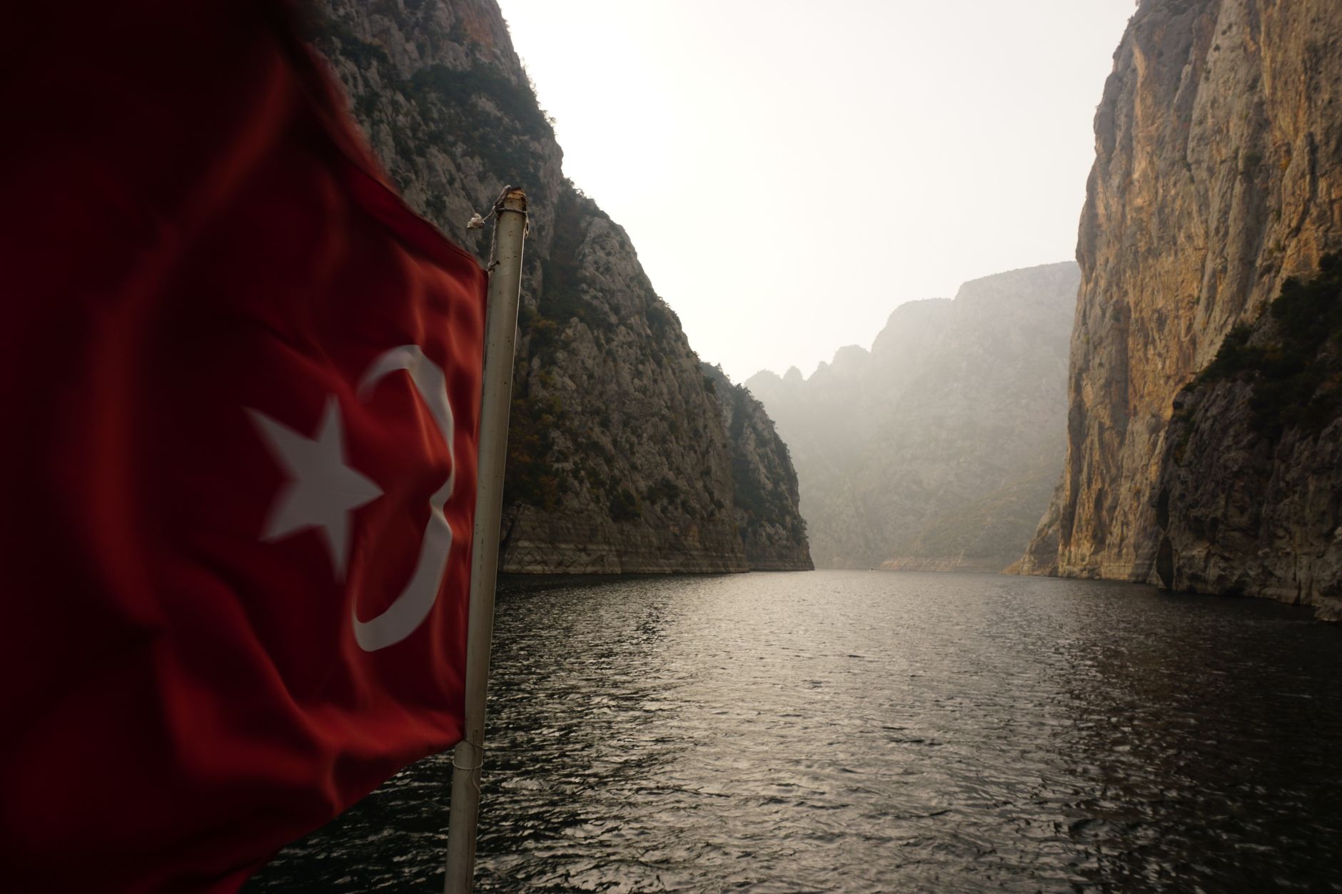 satire-image-80 Trump Turkey satire image: A serene view of a canyon river with a Turkish flag in the foreground. Perfect for travel and nature themes.