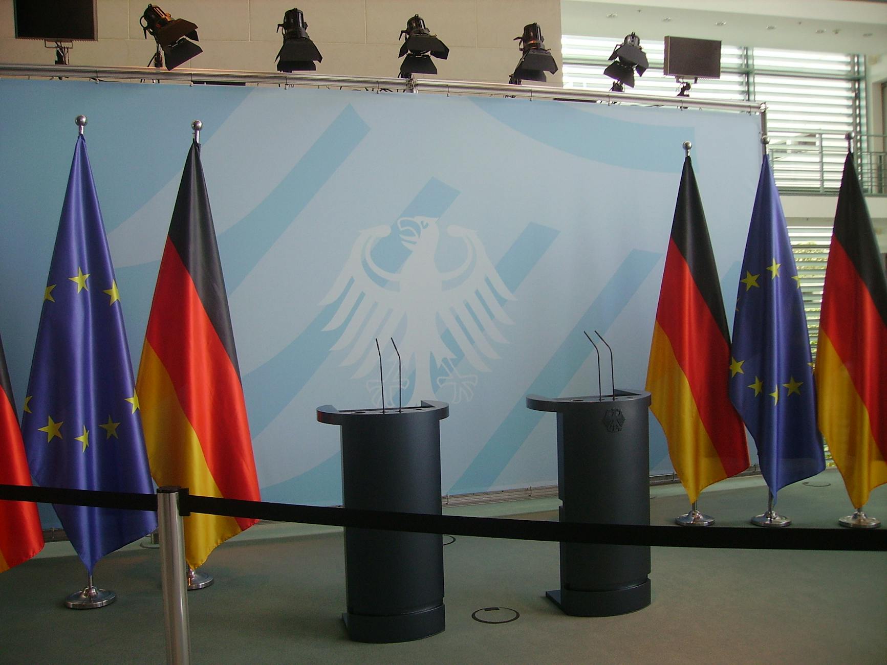 Trump Drafts satire image: Empty podiums with German and EU flags in Federal Chancellery, Berlin.